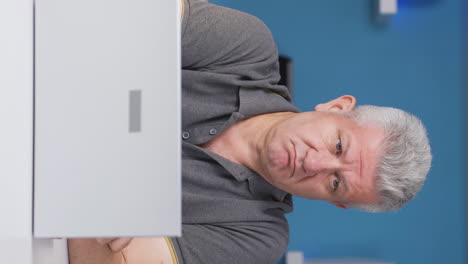 Vertical-video-of-Home-office-worker-man-thinking-looking-at-camera.